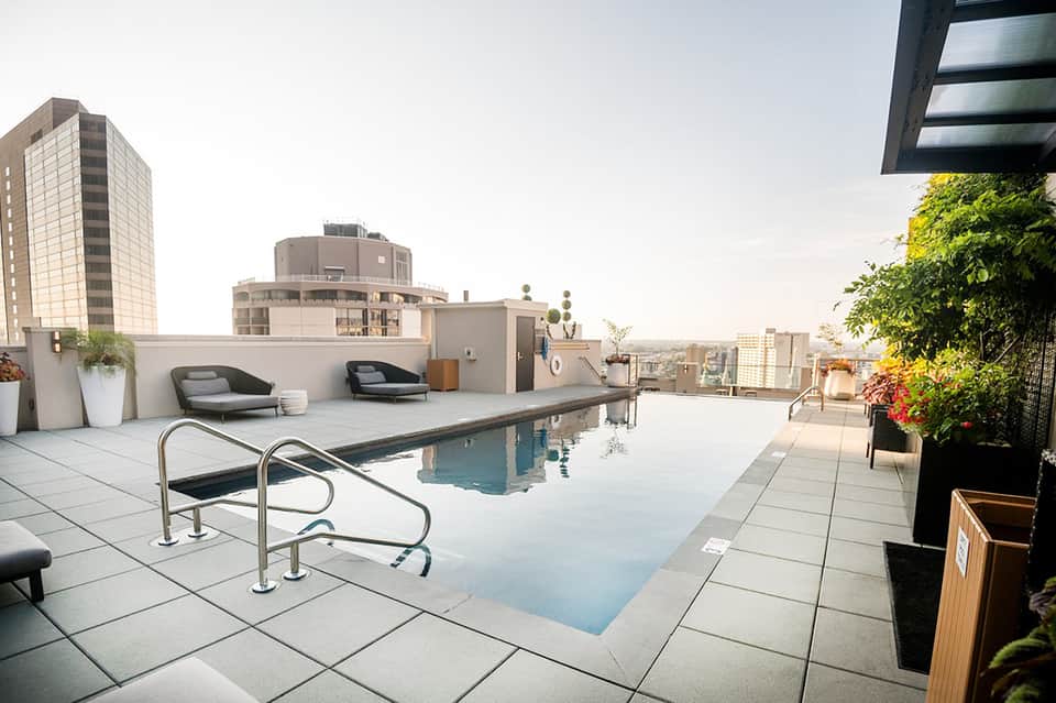 Rooftop pool deck with loungers, city skyline views, and modern architectural elements