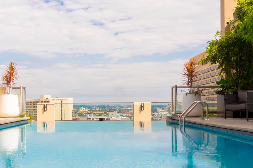 Rooftop infinity pool overlooking city skyline with palm trees and modern hotel architecture