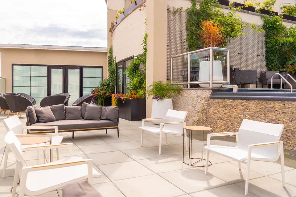 Contemporary patio with modern white and gray seating, vertical plantings, and stone fireplace