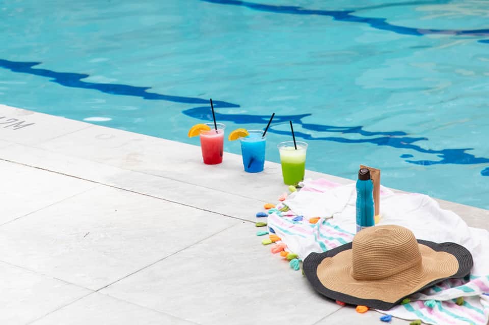 Colorful poolside cocktails and accessories arranged on pool deck