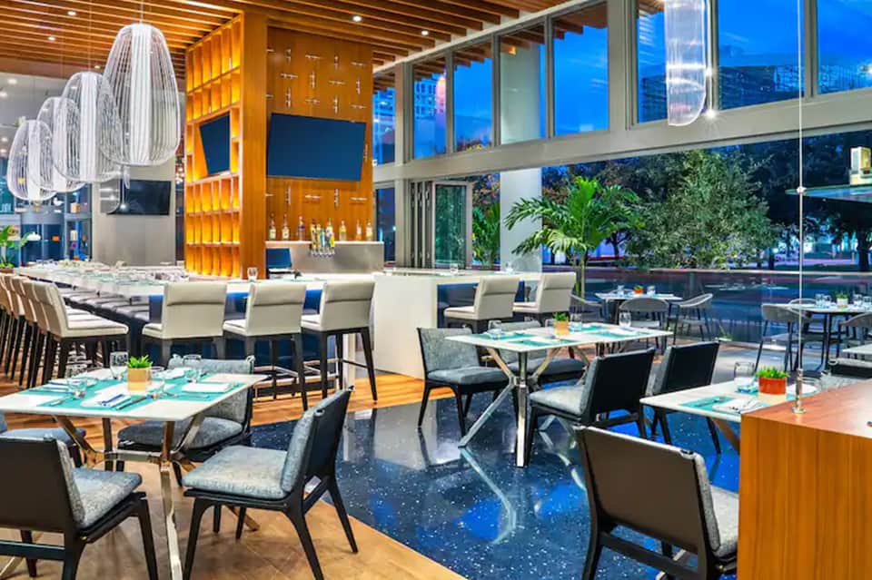 Modern upscale restaurant with floor-to-ceiling windows, city views, and contemporary décor