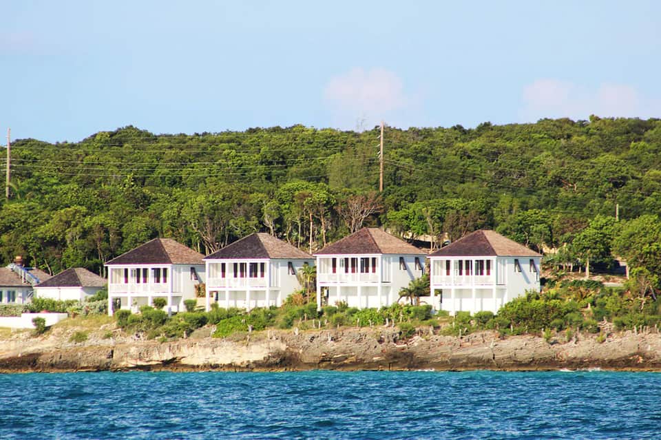 Waterfront homes with white modern architecture on forested hillside overlooking ocean