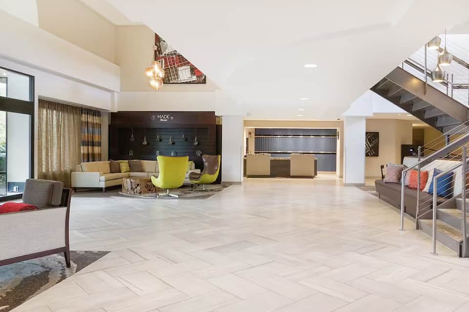 Modern hotel lobby with high ceilings, contemporary furniture, and staircase