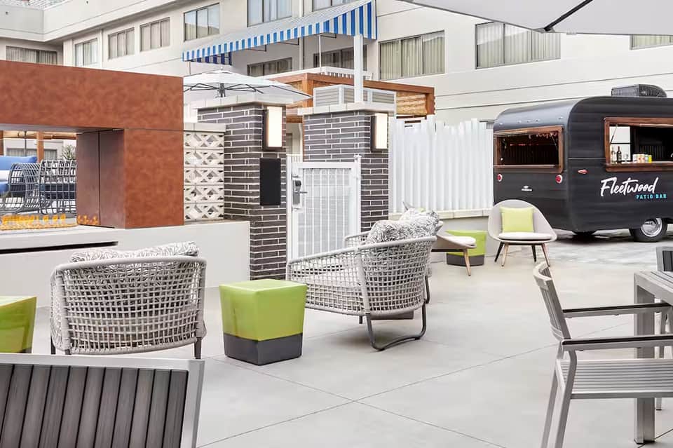 Modern resort courtyard with white wicker chairs, food truck, and contemporary architecture