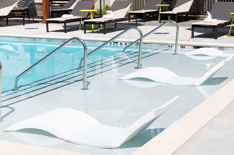 Hot tub and swimming pool area with loungers and yellow accent furniture