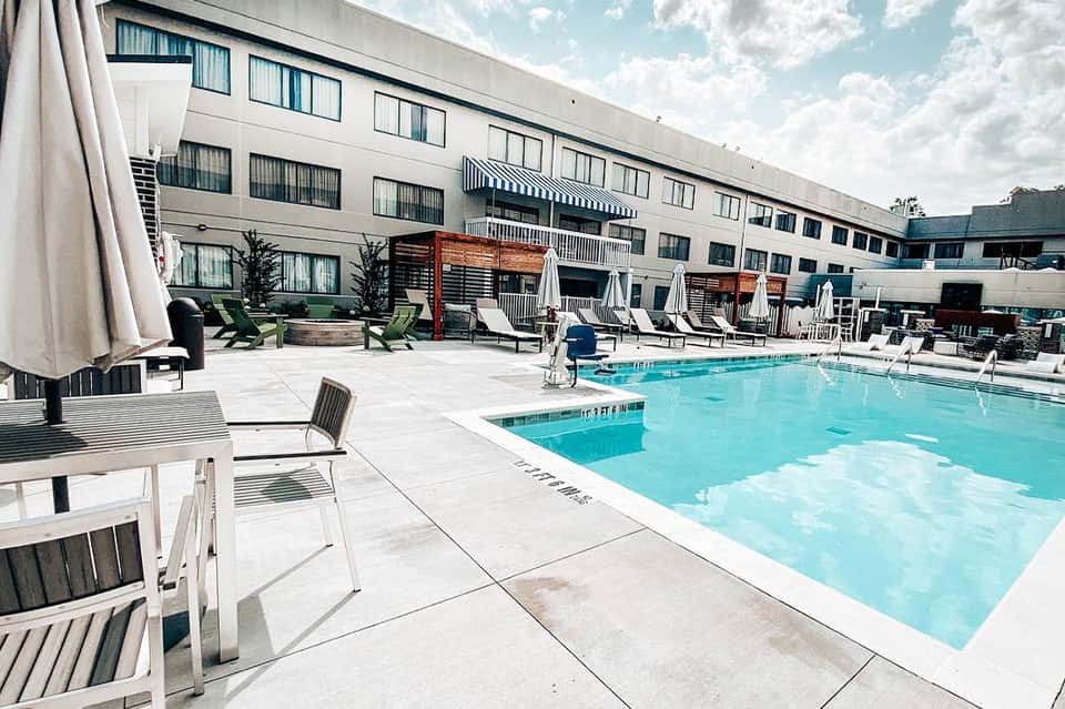 Hotel pool deck with lounge chairs, umbrellas, and modern building facade