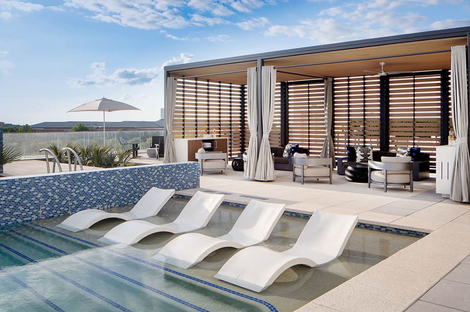Modern resort pool with sunbed loungers, blue tile accent, covered cabana structure, and mountain views