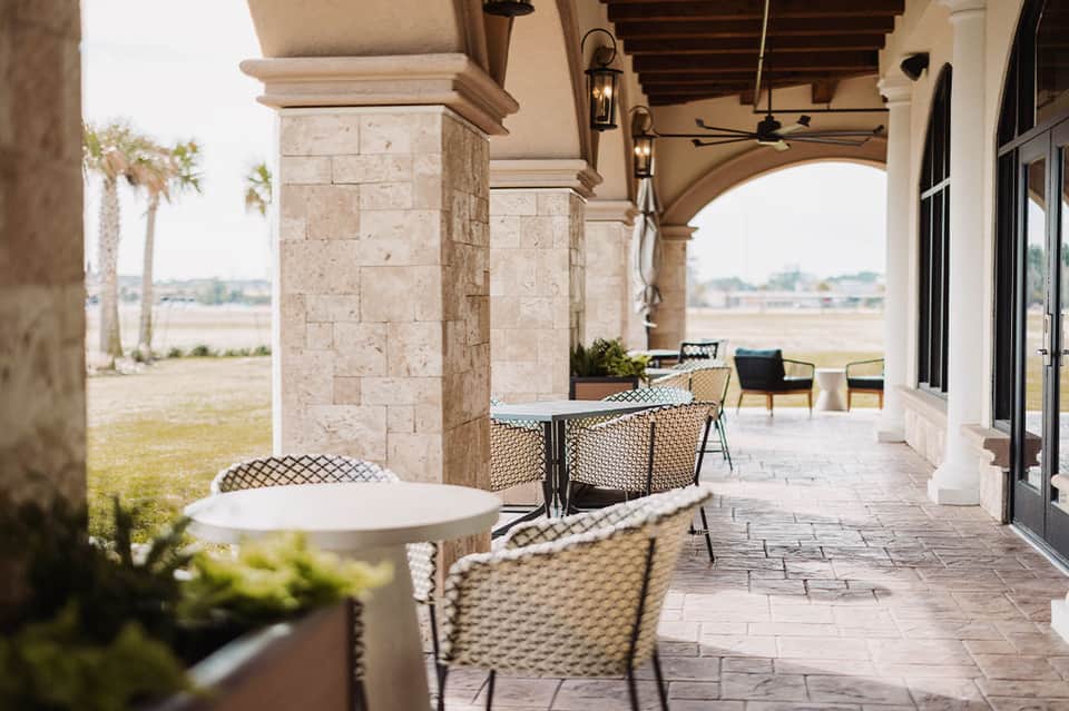 Covered patio with stone columns, comfortable seating, and open courtyard overlooking landscaped grounds