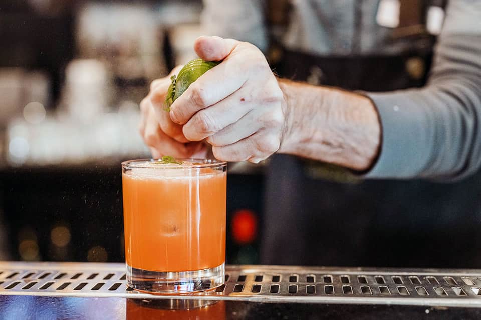 Bartender garnishing a cocktail with fresh lime at hotel bar counter