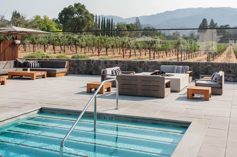 Resort pool overlooking vineyard landscape with lounge seating and fire pit