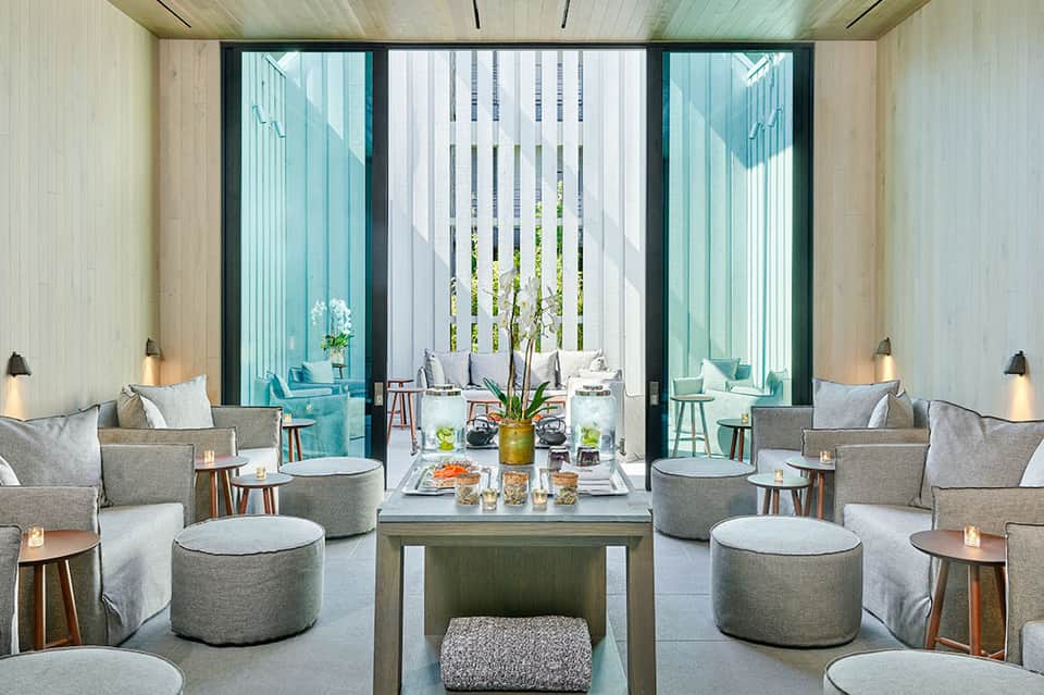 Modern lounge with gray seating, turquoise glass doors, and minimalist decor