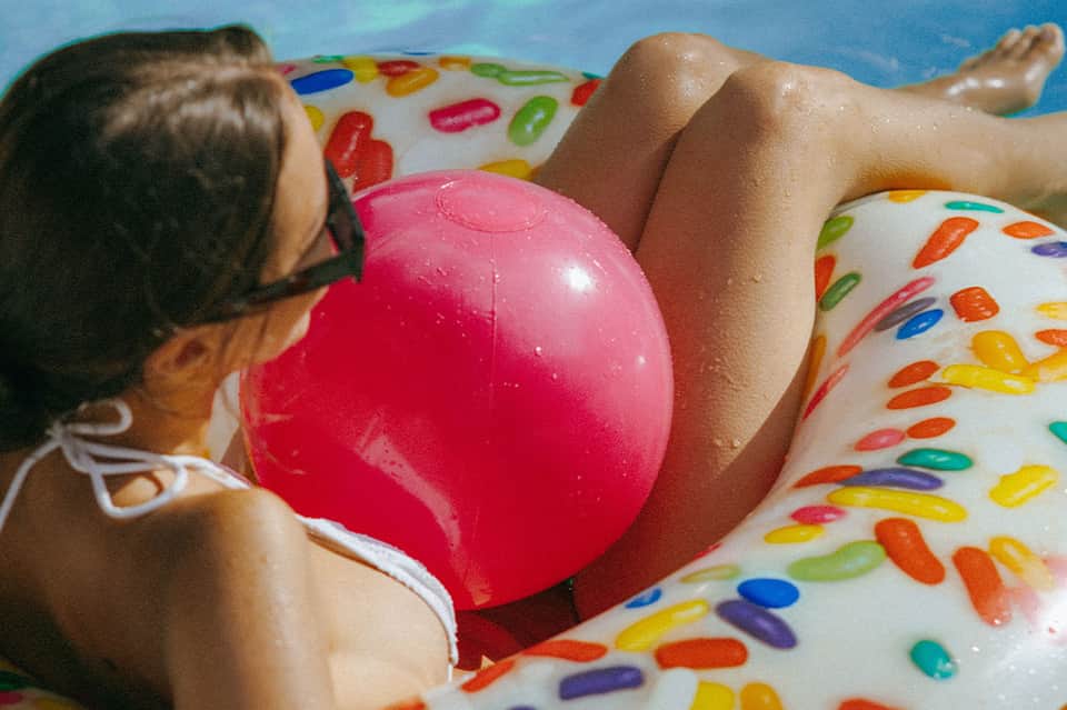 Child floating on colorful pool float in swimming pool