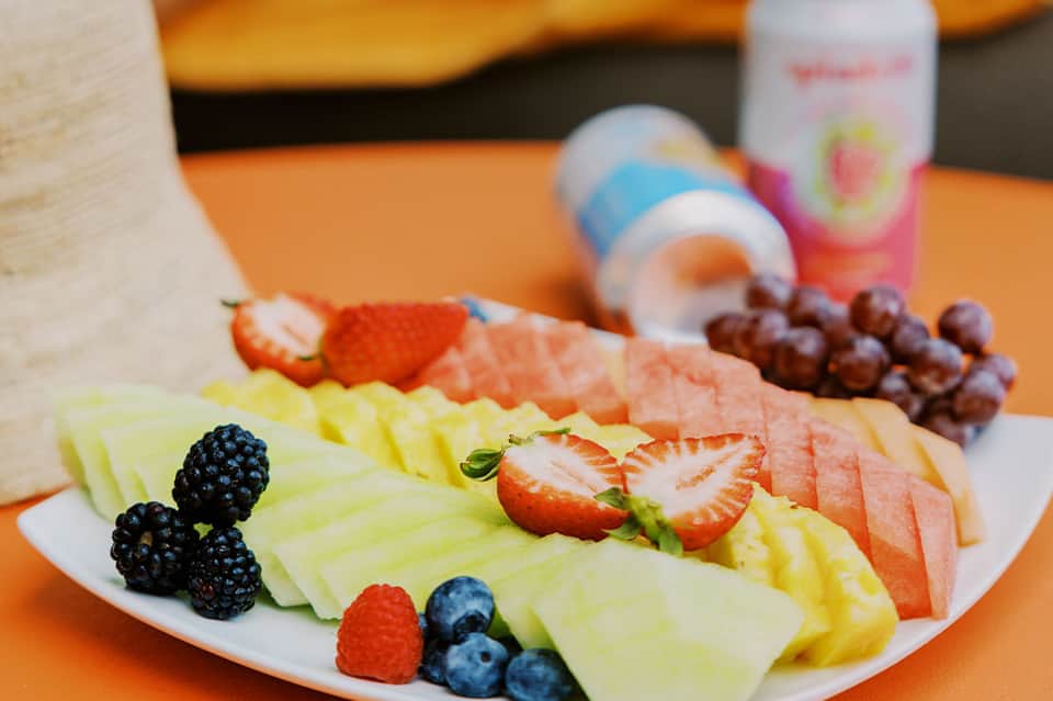 Fresh fruit platter with strawberries, melon, grapes, and berries on orange background