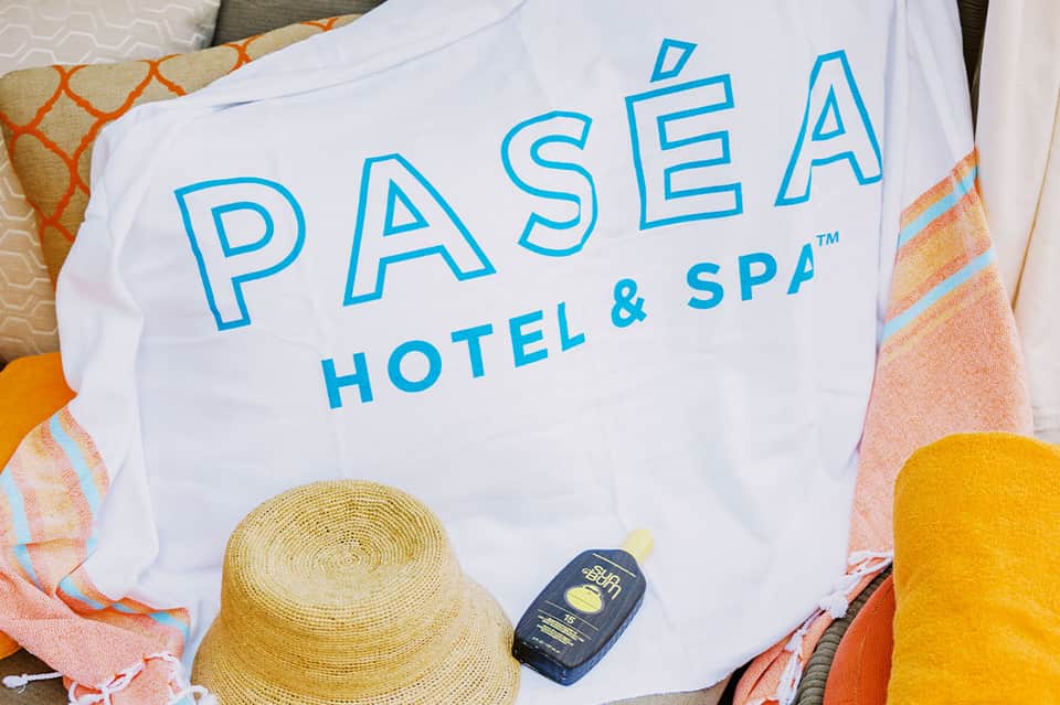 Pasea Hotel & Spa branded beach towel with straw hat and sunscreen bottle on lounge chair