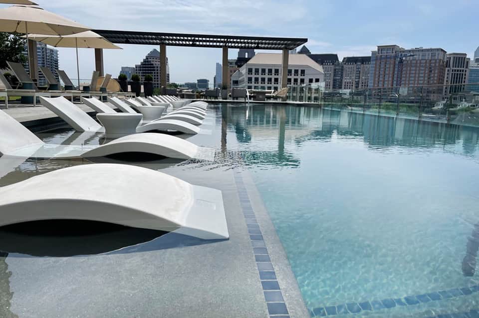 Modern rooftop infinity pool overlooking downtown city skyline and buildings