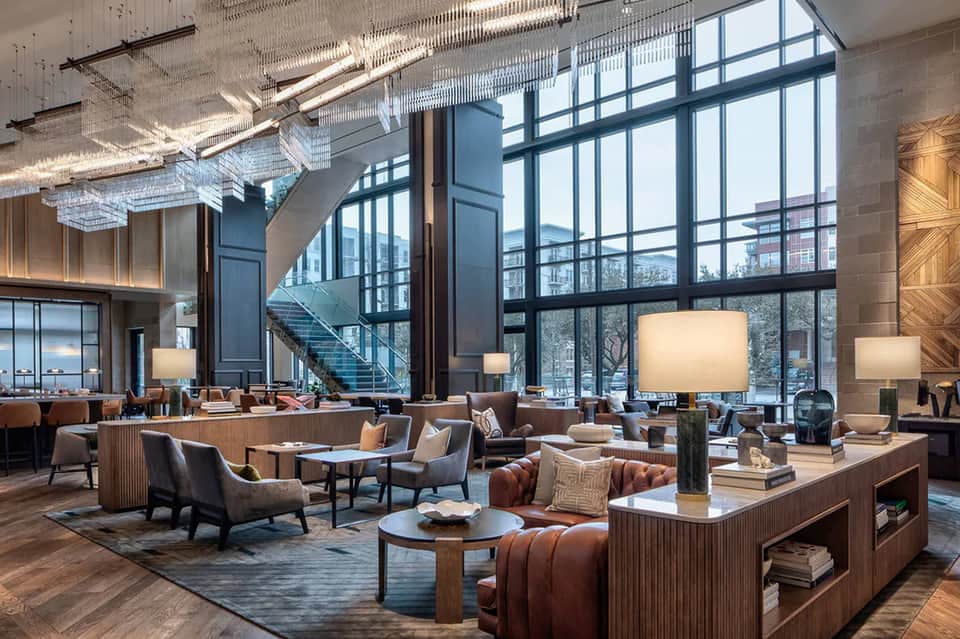 Modern hotel lobby with floor-to-ceiling windows, contemporary furniture, and city skyline views