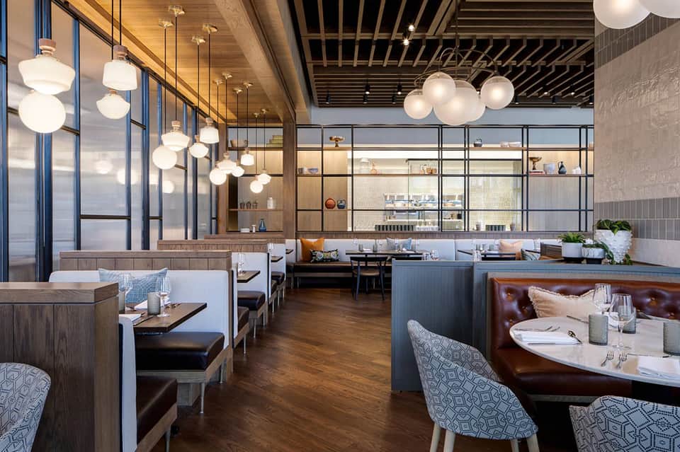 Modern upscale restaurant interior with pendant lights, booth seating, and floor-to-ceiling windows