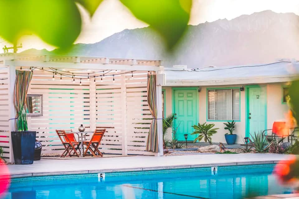 Mid-century modern poolside cabana with turquoise doors and mountain backdrop
