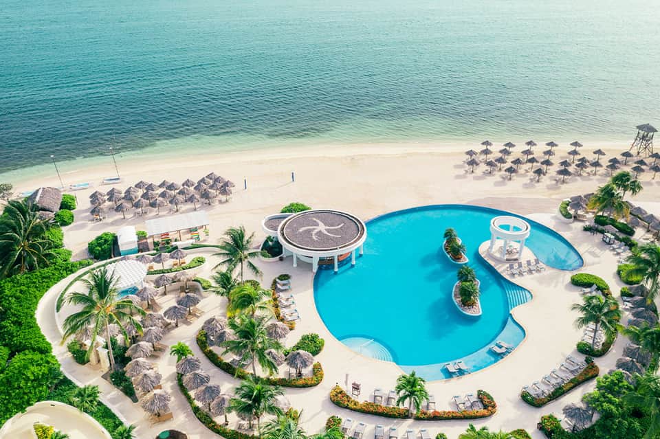 Aerial view of turquoise pool and beach at tropical resort