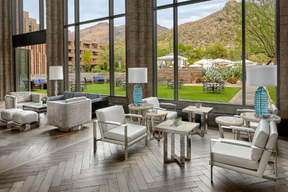 Modern lounge with floor-to-ceiling windows overlooking manicured lawn and desert mountain landscape