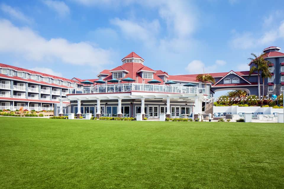 Grand beachfront resort with red roof and manicured lawn overlooking ocean