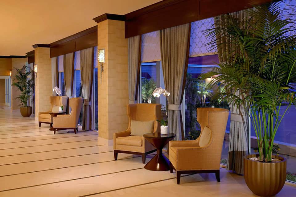 Elegant evening terrace with gold accent chairs, columns, and ocean view through glass doors