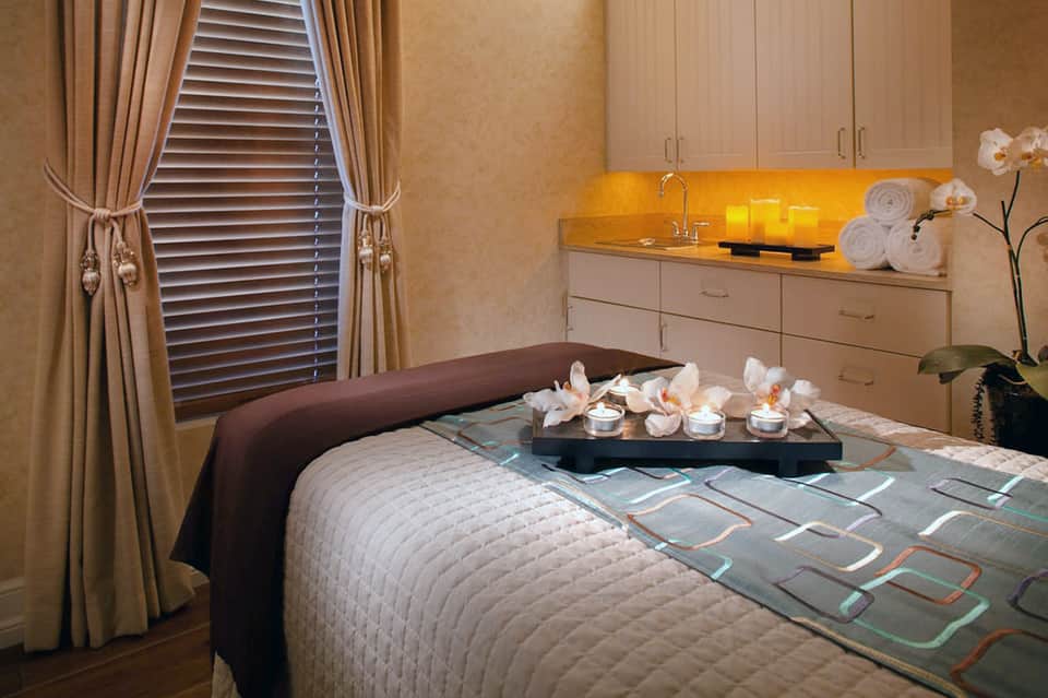 Spa treatment room with massage bed, orchid flowers, amber lighting, and calming neutral décor