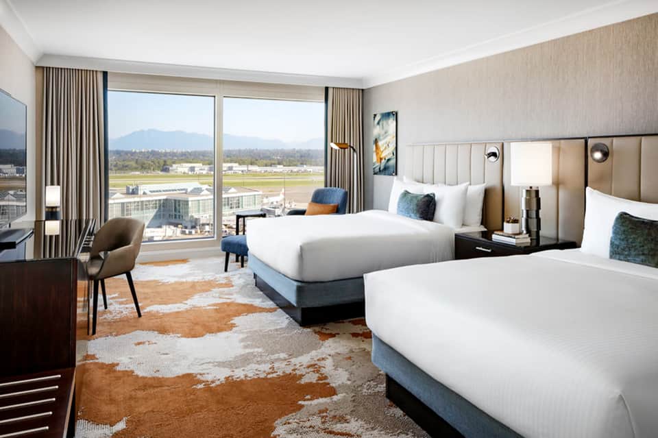 Luxury hotel room with mountain views, two queen beds, modern furnishings, and floor-to-ceiling windows