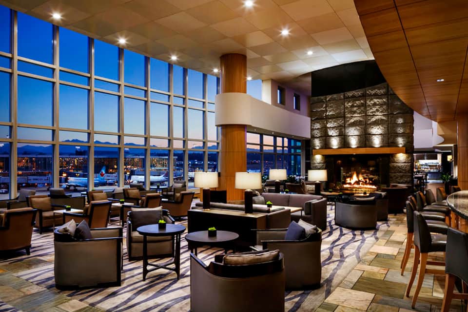 High-rise hotel lounge with panoramic city views, stone fireplace, modern furnishings, and evening ambiance