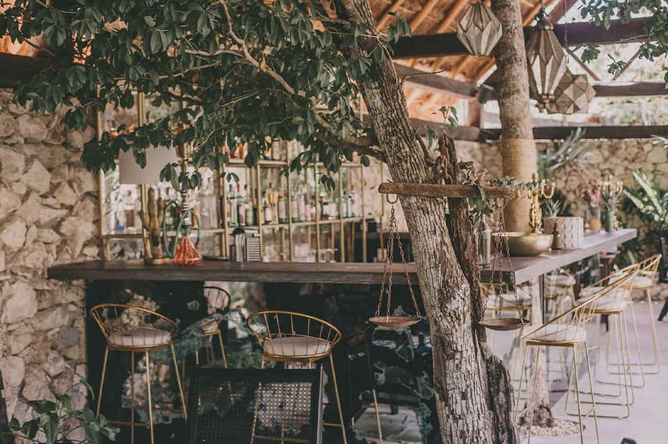 Rustic courtyard bar with stone walls, wooden chairs, and vintage decorative elements
