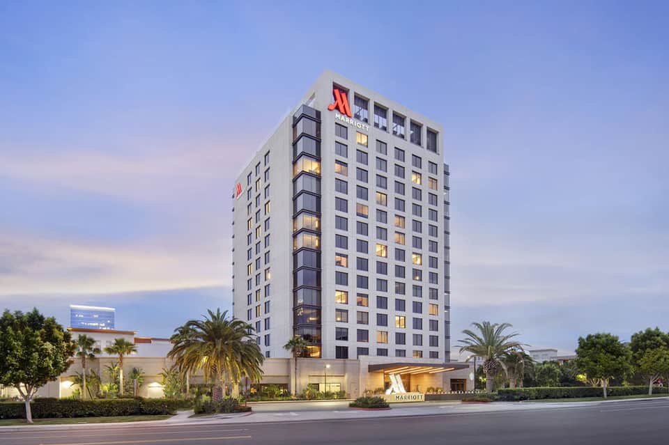 Modern Marriott hotel exterior at dusk with illuminated rooms, palm landscaping, and welcoming entrance