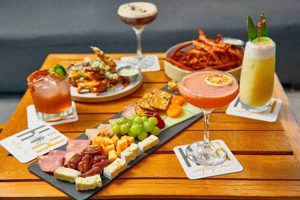 Gourmet food and cocktails displayed on wooden table with appetizers