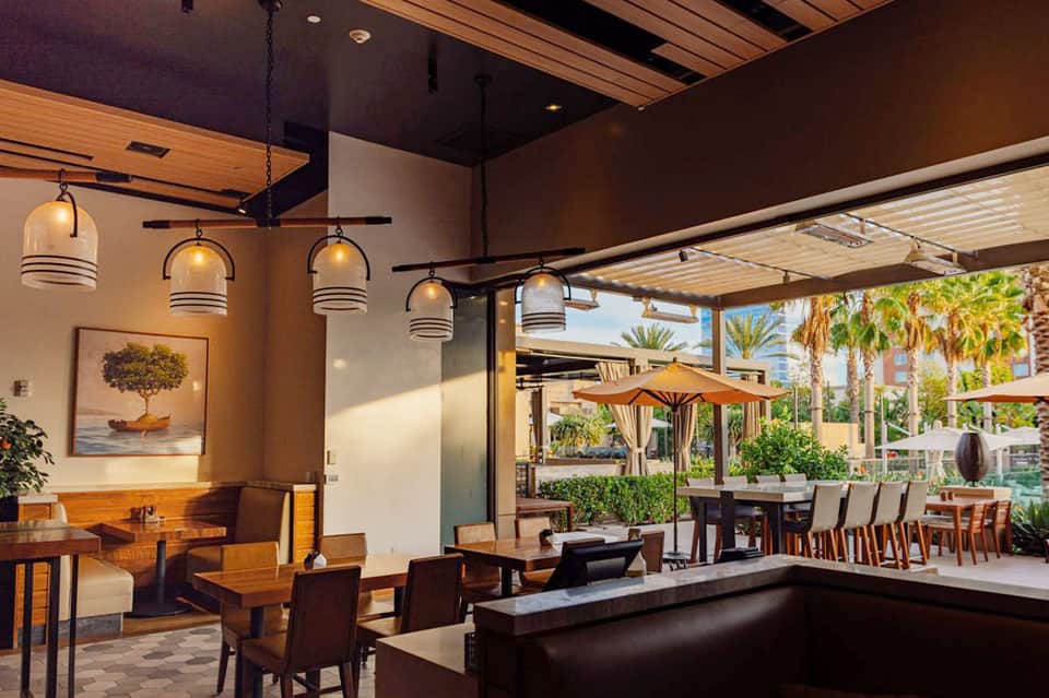 Modern restaurant interior with wooden beams, pendant lights, and outdoor patio seating