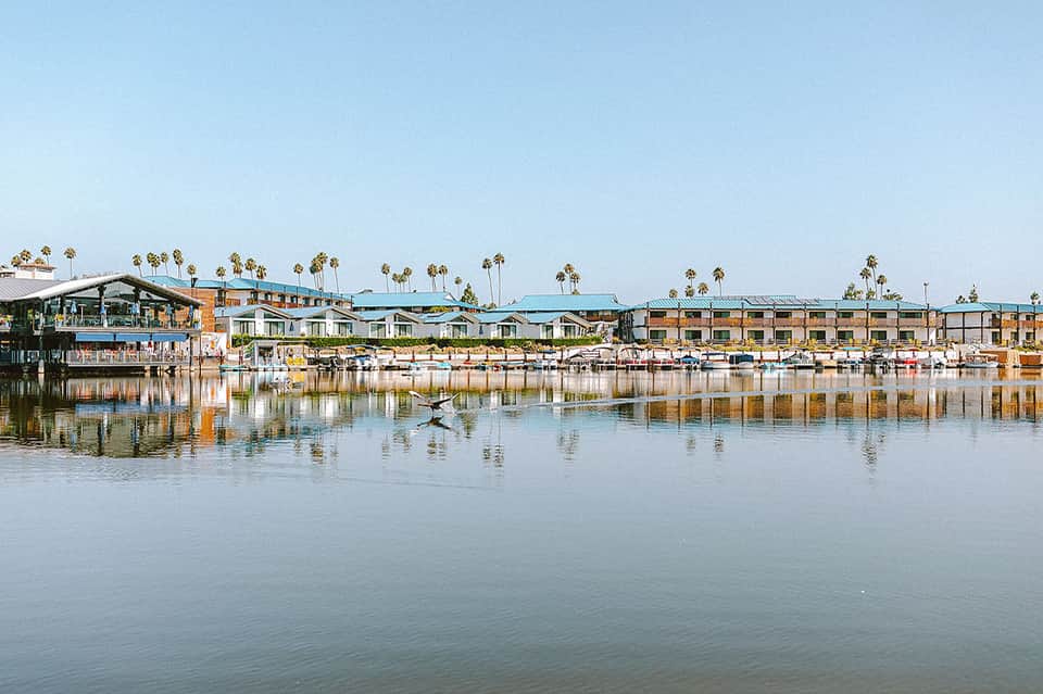 Waterfront resort with turquoise roofs and palm trees reflected in calm bay water