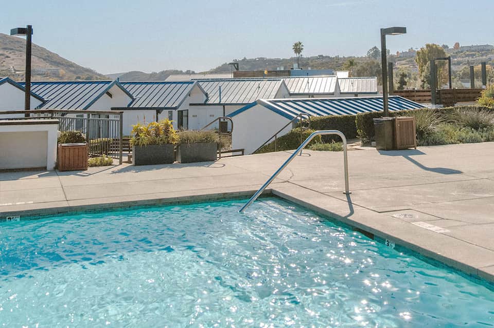 Contemporary resort pool with metal slide, blue and white striped awnings, mountain views, and terracotta patio