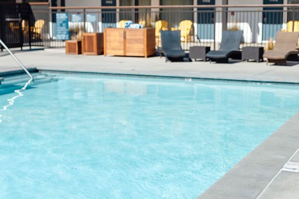 Oceanfront pool with lounge chairs, wooden storage boxes, and coastal railing
