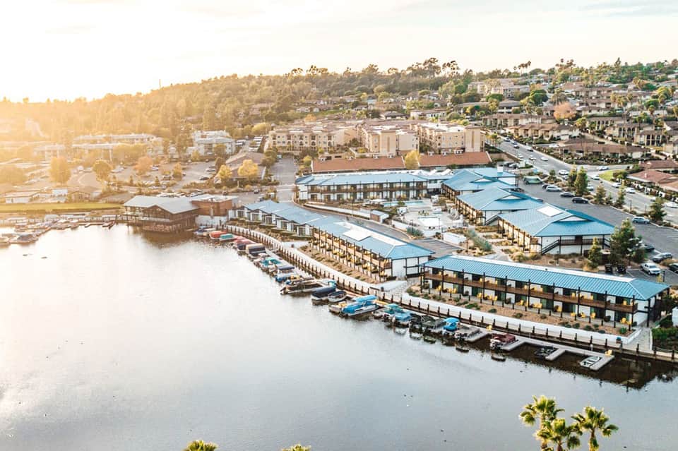 Waterfront resort with blue metal-roofed buildings along calm river at golden hour