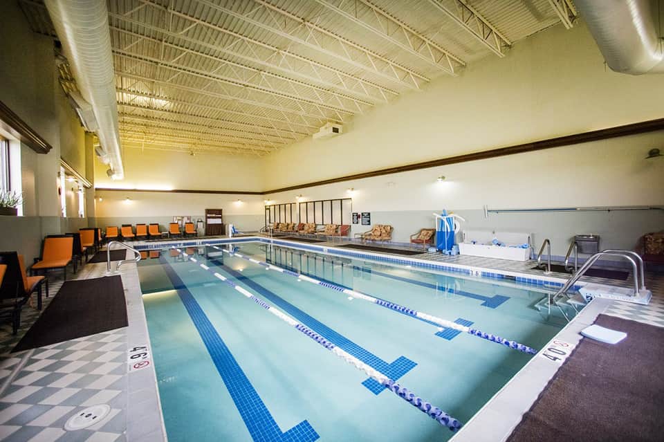 Indoor lap pool facility with multiple swimming lanes and spectator seating in bright gymnasium