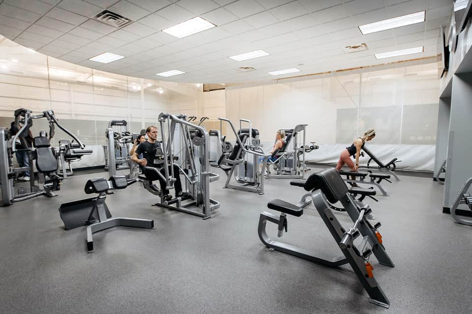 Modern fitness center with exercise equipment and people working out