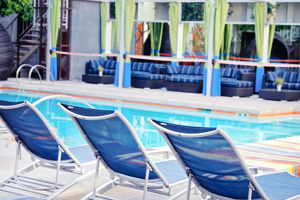 Resort pool with blue lounge chairs and striped cushioned seating on the deck