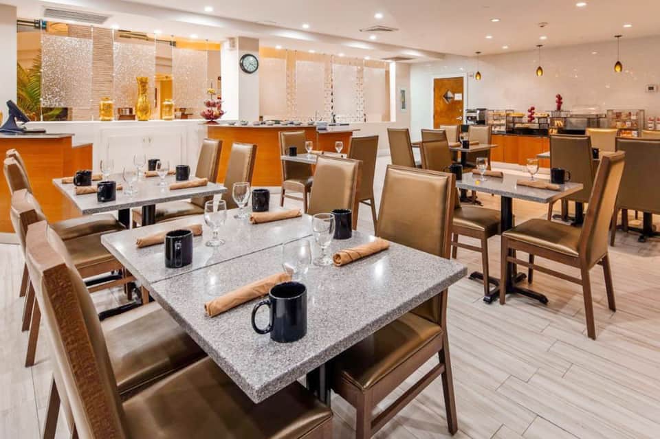 Elegant dining room with granite-top tables, tan chairs, and modern lighting