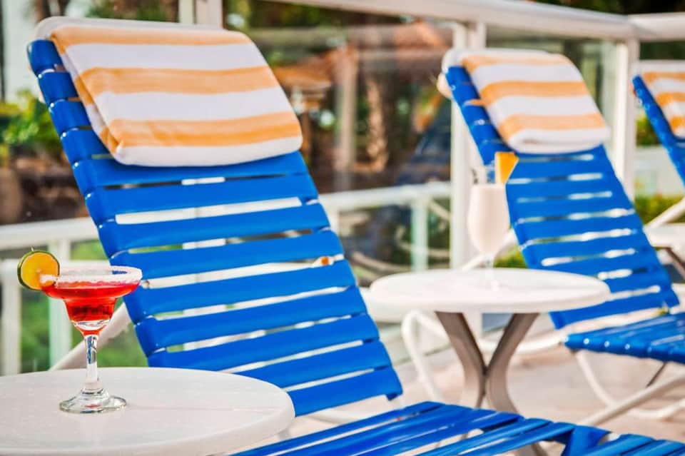 Blue and orange striped lounge chair with tropical cocktail on side table