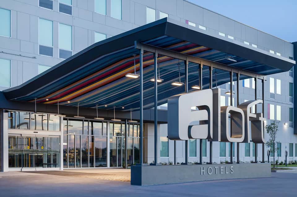 Modern Aloft Hotels entrance with curved black canopy and glass facade at dusk