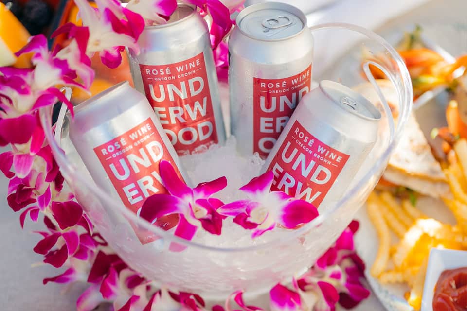 Rosé wine cans in ice bucket surrounded by colorful flower petals