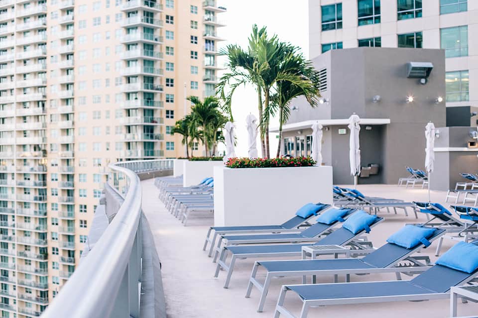 High-rise rooftop pool deck with lounge chairs and city skyline backdrop