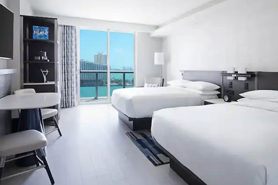 Modern hotel room with twin beds, ocean view balcony, and contemporary furnishings