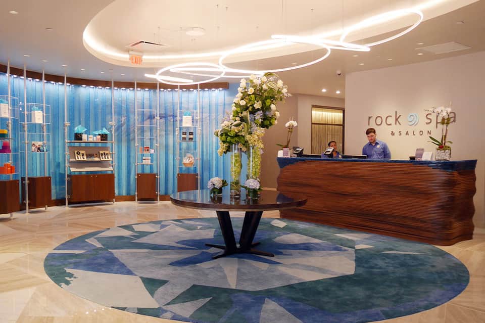 Modern spa reception with curved lighting, wooden desk, and blue curtain walls