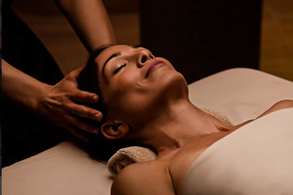 Woman receiving professional head and neck massage in spa treatment room