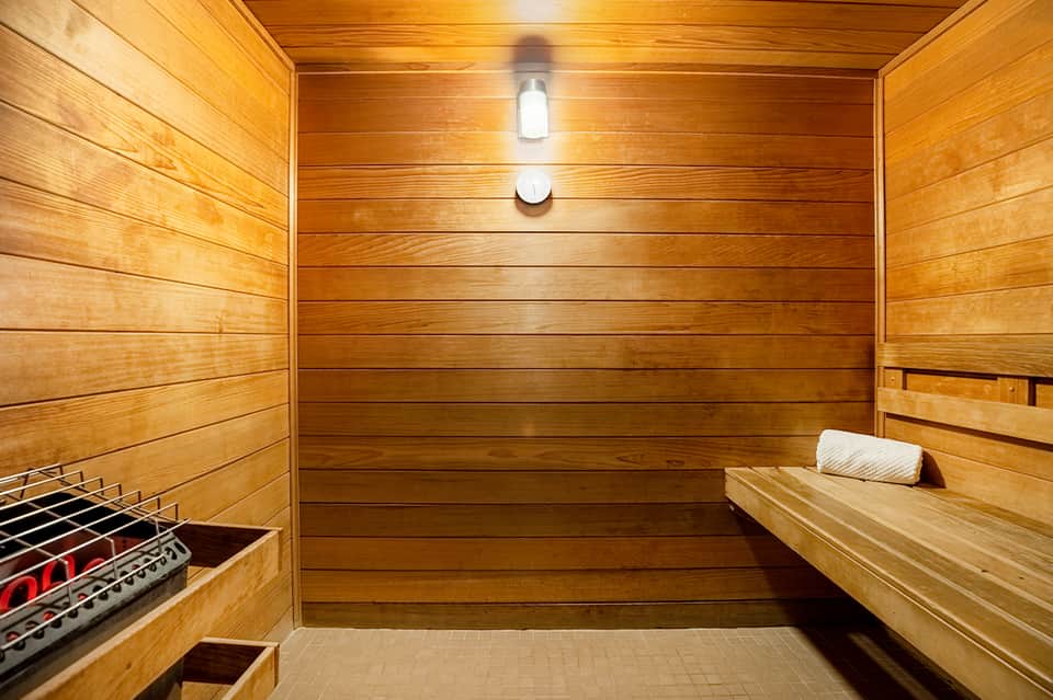 Wooden sauna interior with bench seating, heater, and ambient lighting