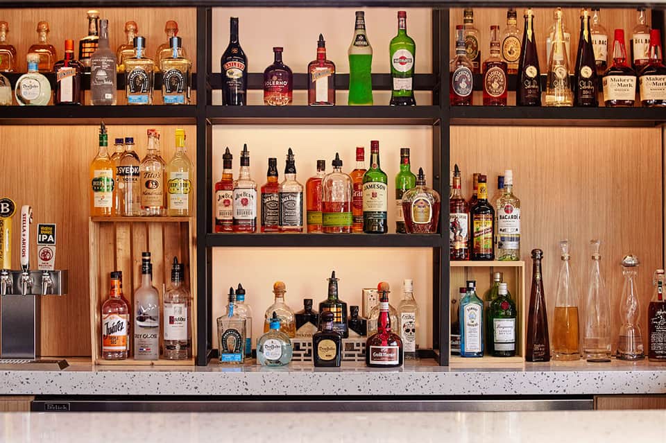 Well-stocked bar shelving displaying various liquor bottles and spirits